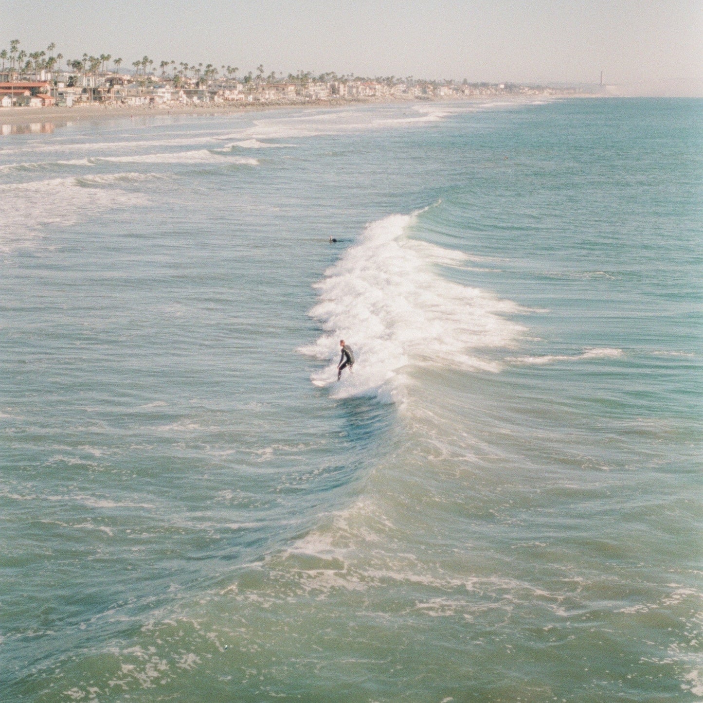 Surfer riding a large wave with a beach