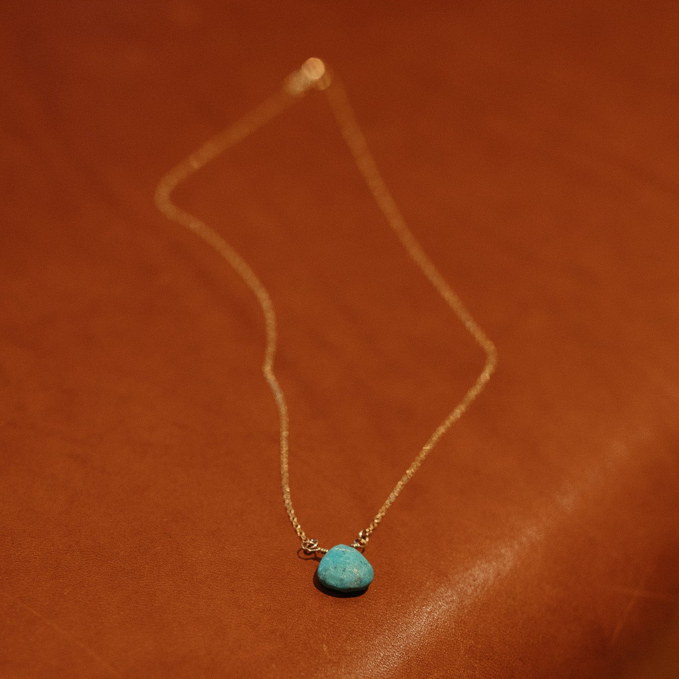 Necklace with a turquoise pendant on a brown leather surface
