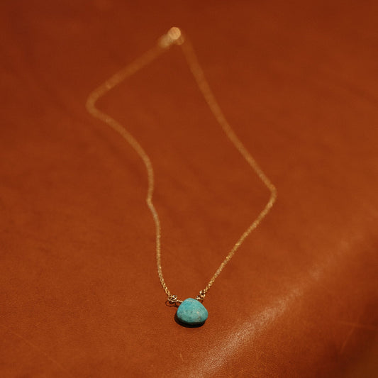 Turquoise Briolette Necklace with a gold chain on brown leather.