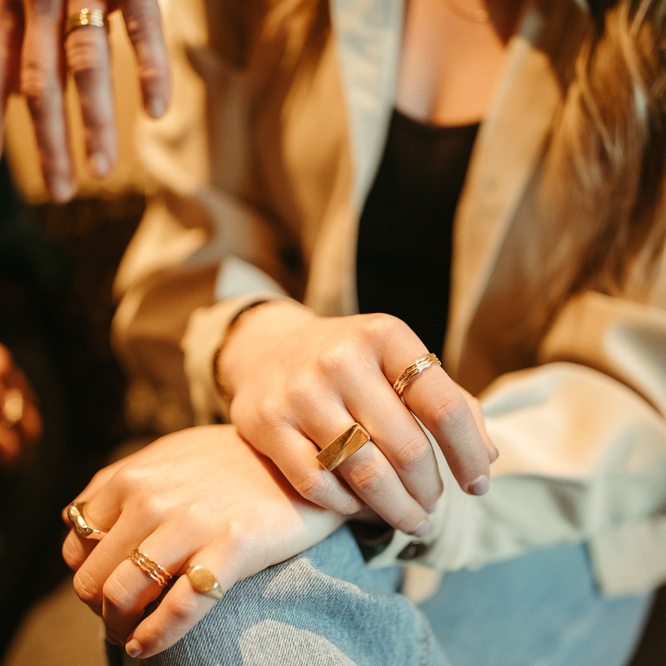 Woman wearing gold signet ring on pinky finger, minimalist jewelry style