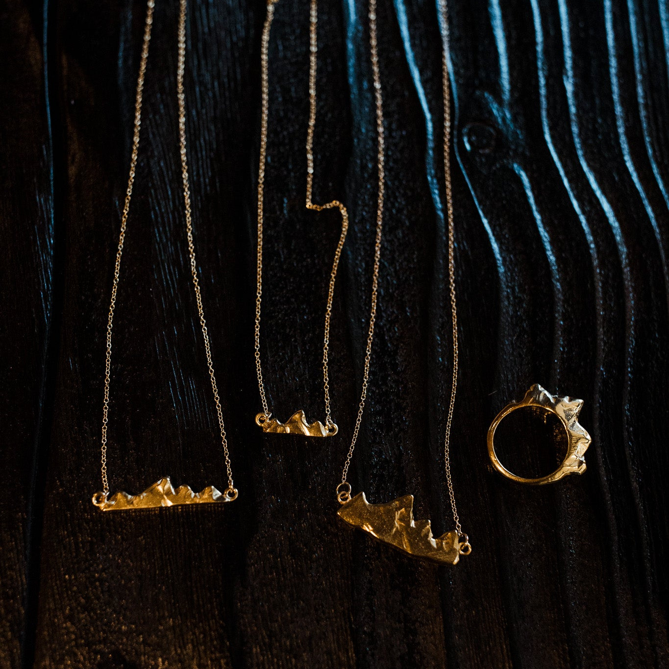 Teton I, II, and III necklaces on black wooden surface showing size and detail