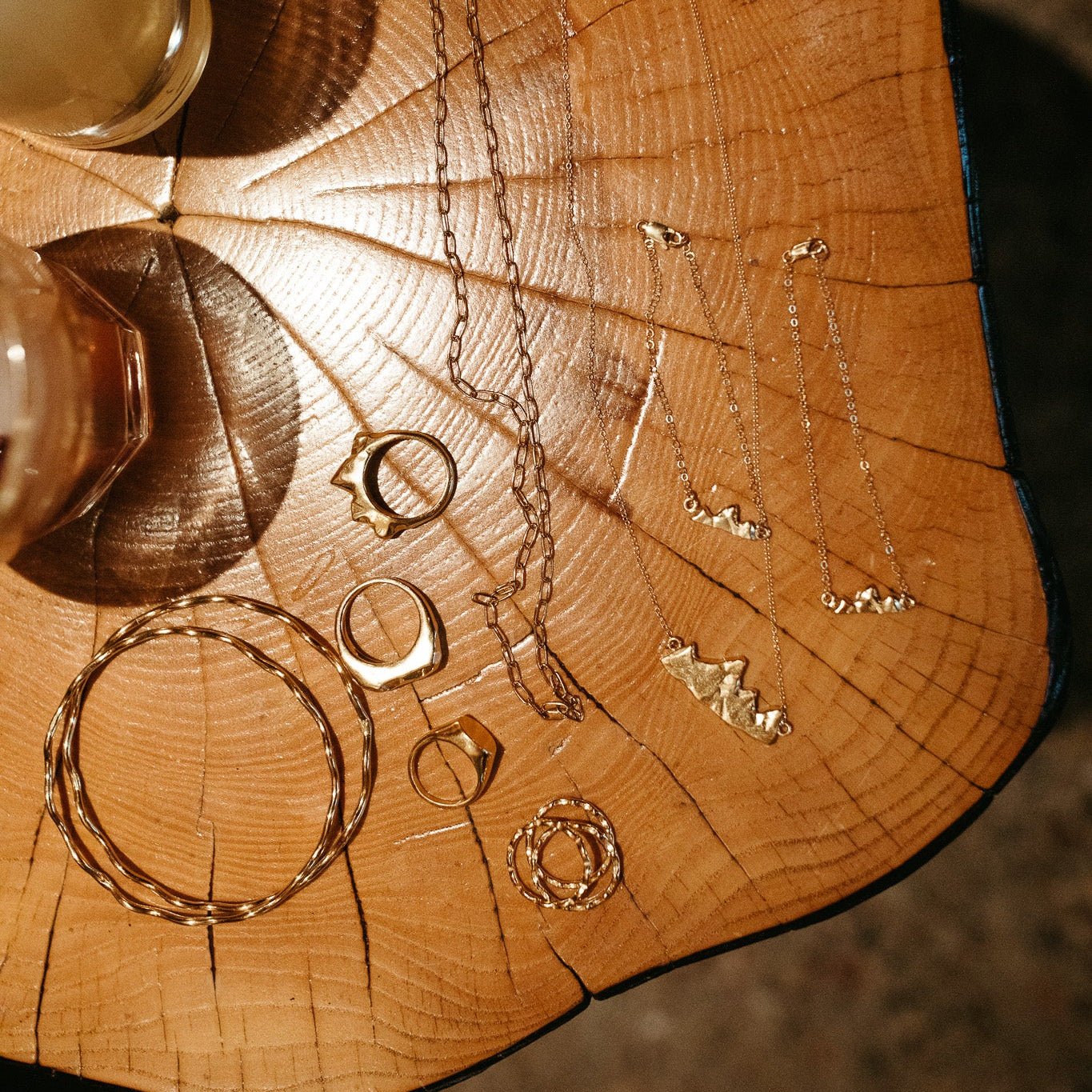 Close-up of Teton pendant charm on gold-filled chain bracelet on wooden surface