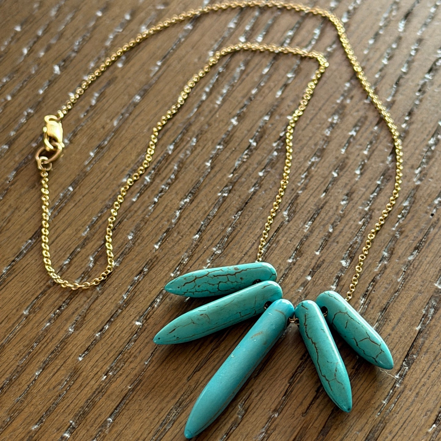 Close-up of natural marbled Turquoise Howlite spikes showing unique turquoise veining and gold-filled findings
