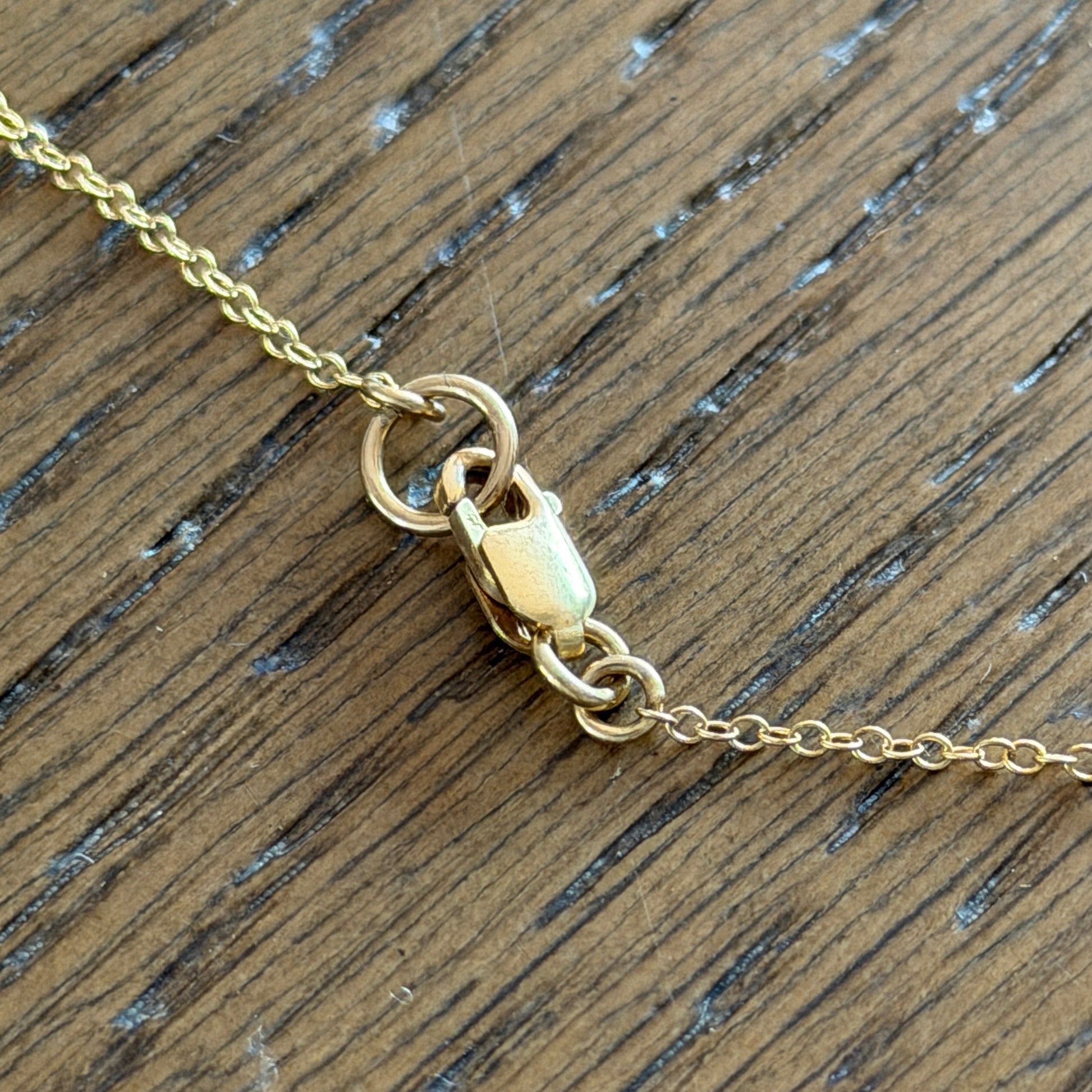 Gold filled necklace chain with clasp on a wooden surface
