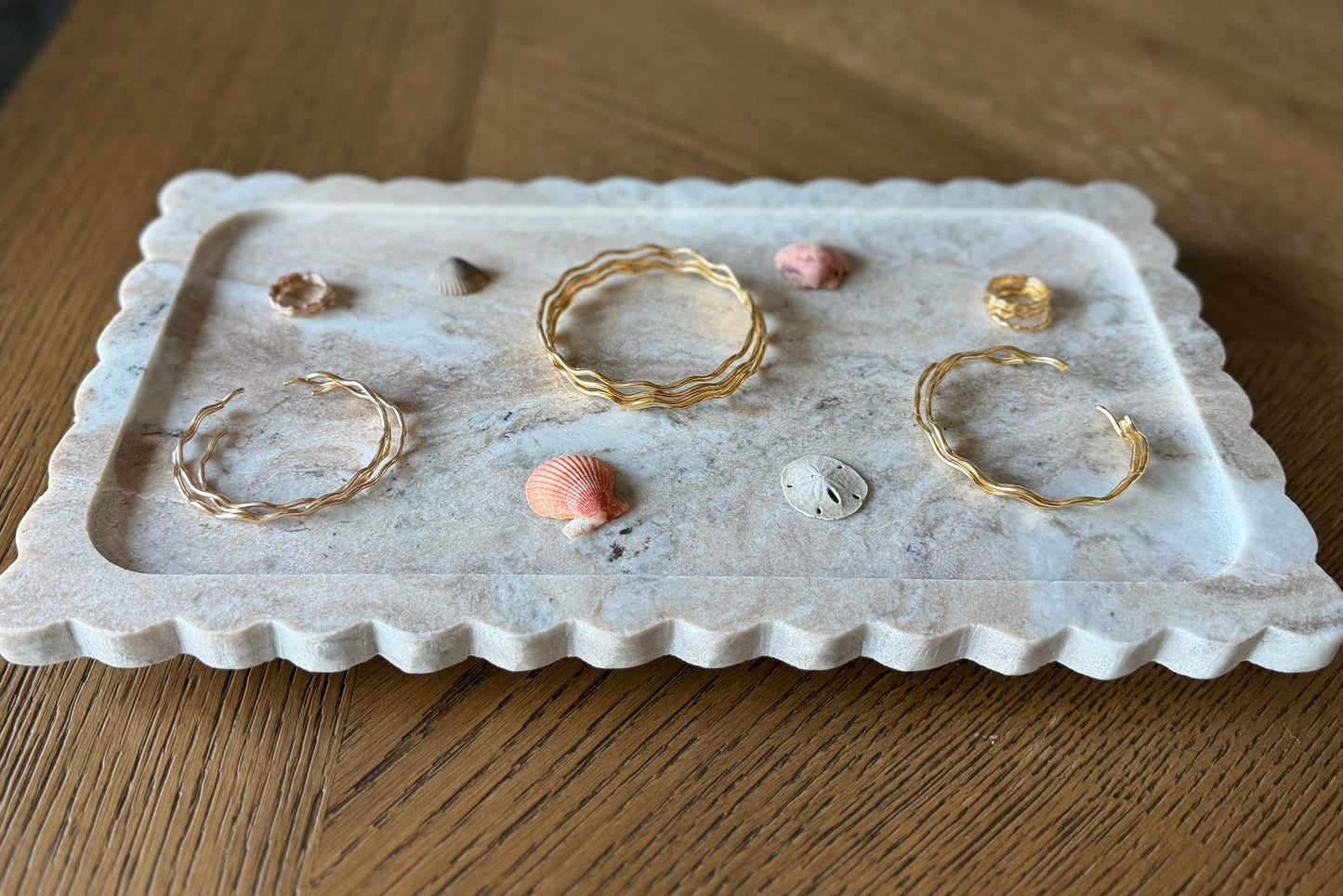 Gold jewelry on a decorative stone tray on a wooden surface