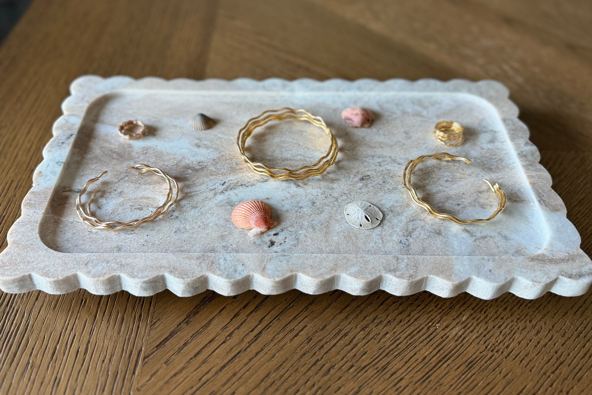 Gold jewelry on a decorative stone tray on a wooden surface