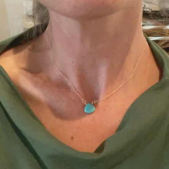 Video showing the Turquoise Briolette Necklace on a model, demonstrating how the 15-inch gold-filled chain sits at collarbone length and how the faceted turquoise teardrop catches light with movement.