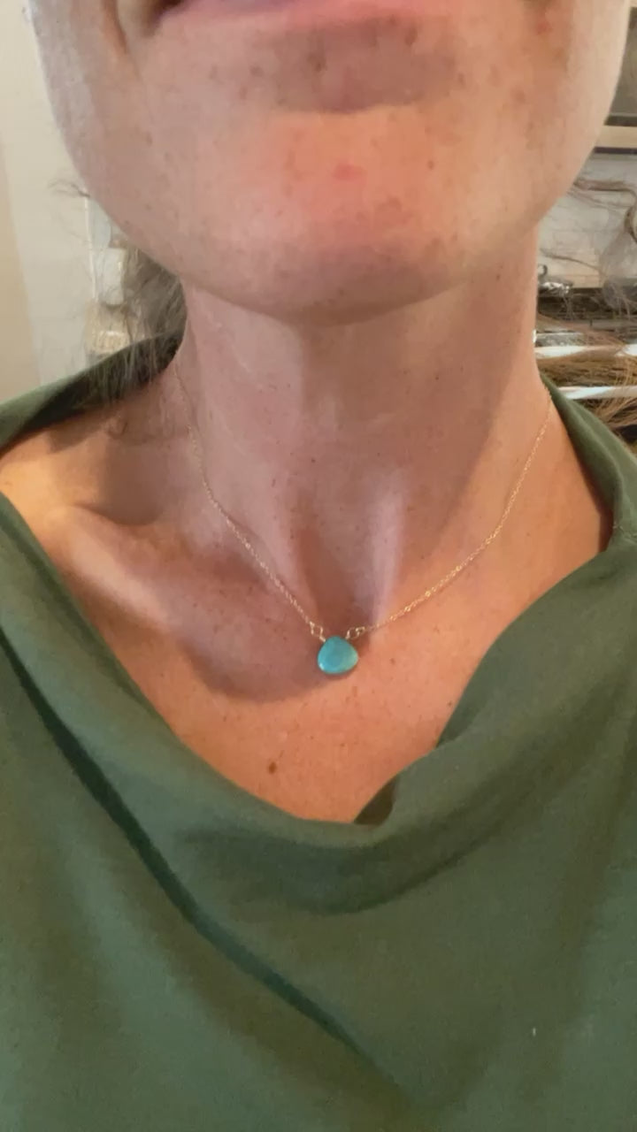 Video showing the Turquoise Briolette Necklace on a model, demonstrating how the 15-inch gold-filled chain sits at collarbone length and how the faceted turquoise teardrop catches light with movement.